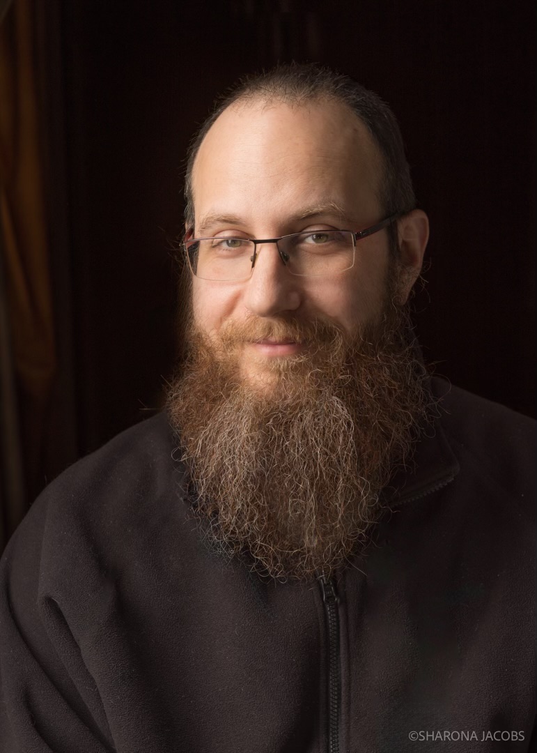 Portraint photo of Jeremy Kriegel. White male. Short hair. Long brown beard. Dark Background.